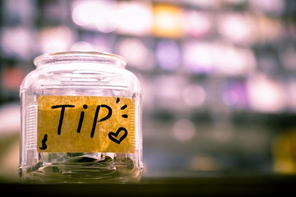 A glass jar with tip written on it.