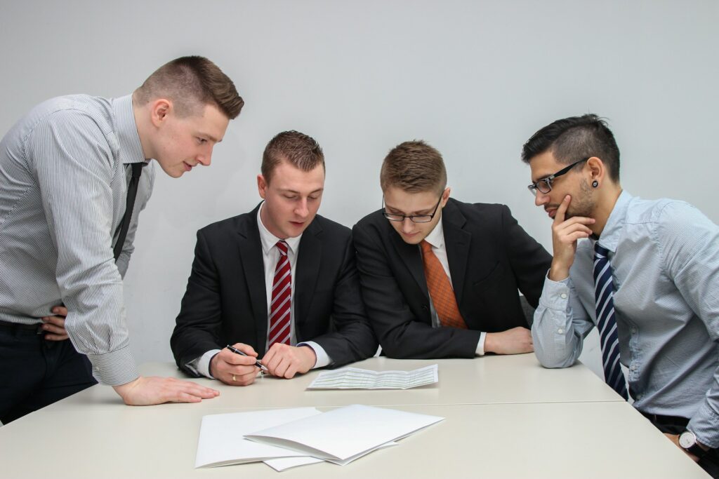 A group of men sitting around a table looking at papers.